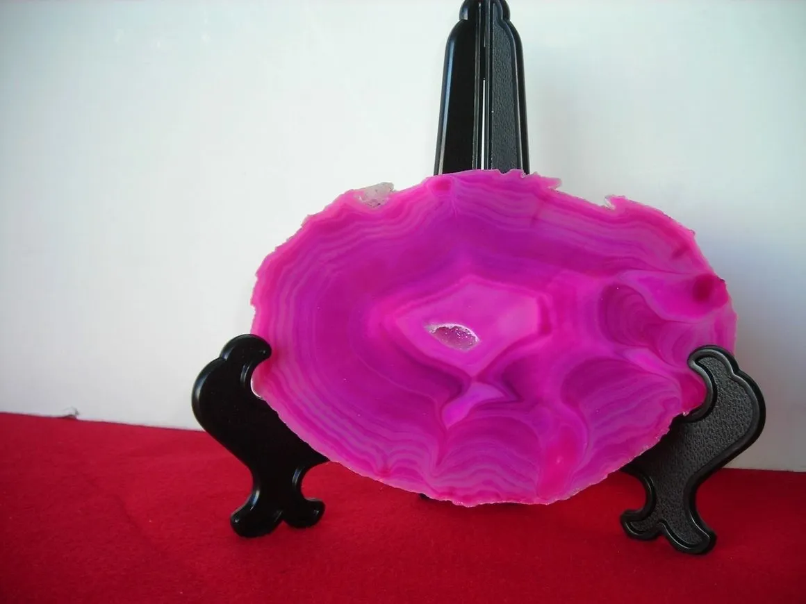 Pink geode slice on black display stand.